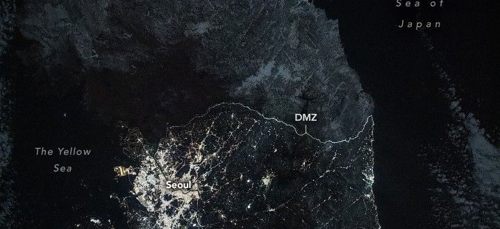 NASA nighttime image of the Korean Peninsula showing South Korea glowing with city lights while North Korea remains largely dark beyond the DMZ.